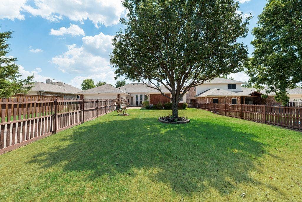 1485 Ashbourne Drive, Rockwall, TX 75087 Expansive grassy yard with a mature shade tree and wood fencing