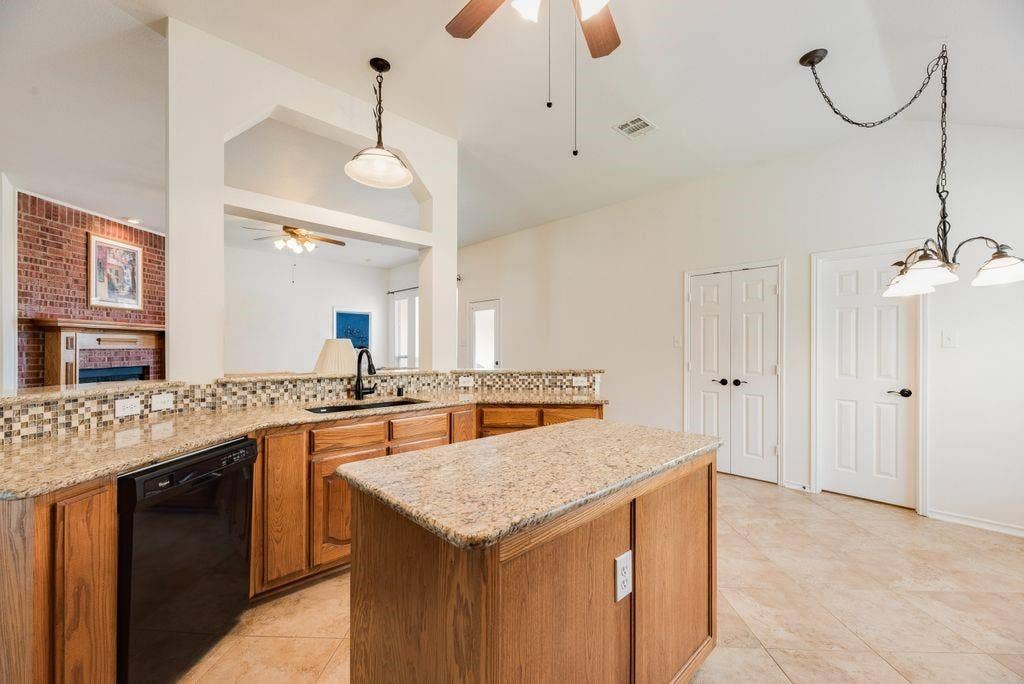 1485 Ashbourne Drive, Rockwall, TX 75087 Kitchen featuring wood cabinetry, granite countertops, tile flooring, and a center island