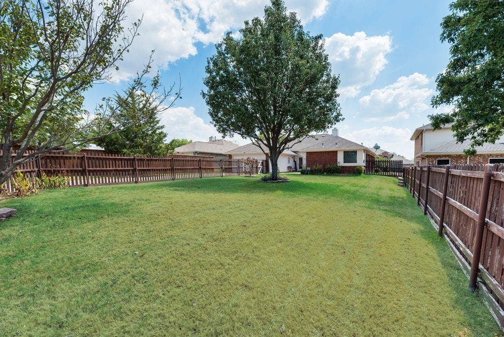 1485 Ashbourne Drive, Rockwall, TX 75087 Expansive green lawn with mature trees and a perimeter wood fence