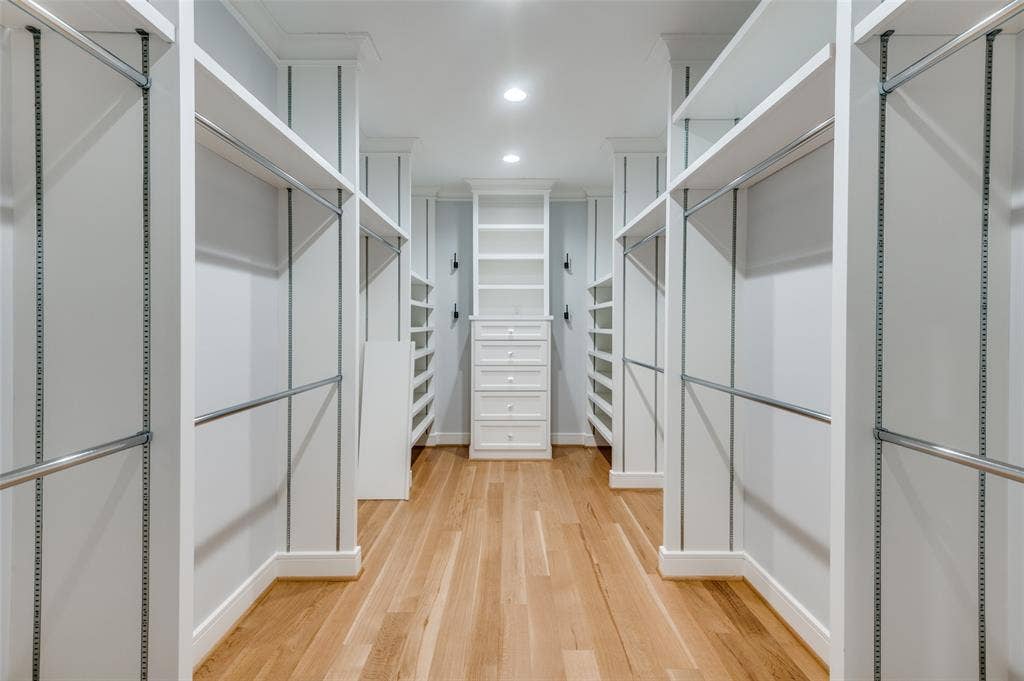 4031 Prescott Avenue, Dallas, TX 75219 Walk-in closet with natural wood-finish flooring, recessed lighting, white built-in shelving, chrome hanging rods, and a central dresser with multiple drawers