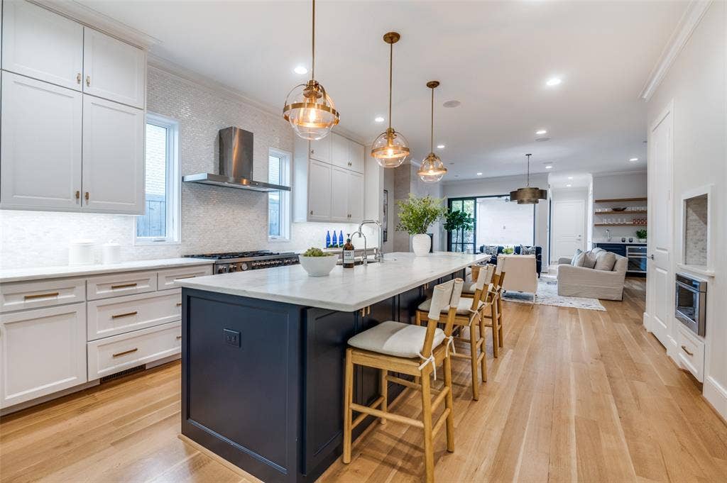 4031 Prescott Avenue, Dallas, TX 75219 Gourmet kitchen with a large center island, white cabinetry, integrated range hood, and light wood-finish flooring