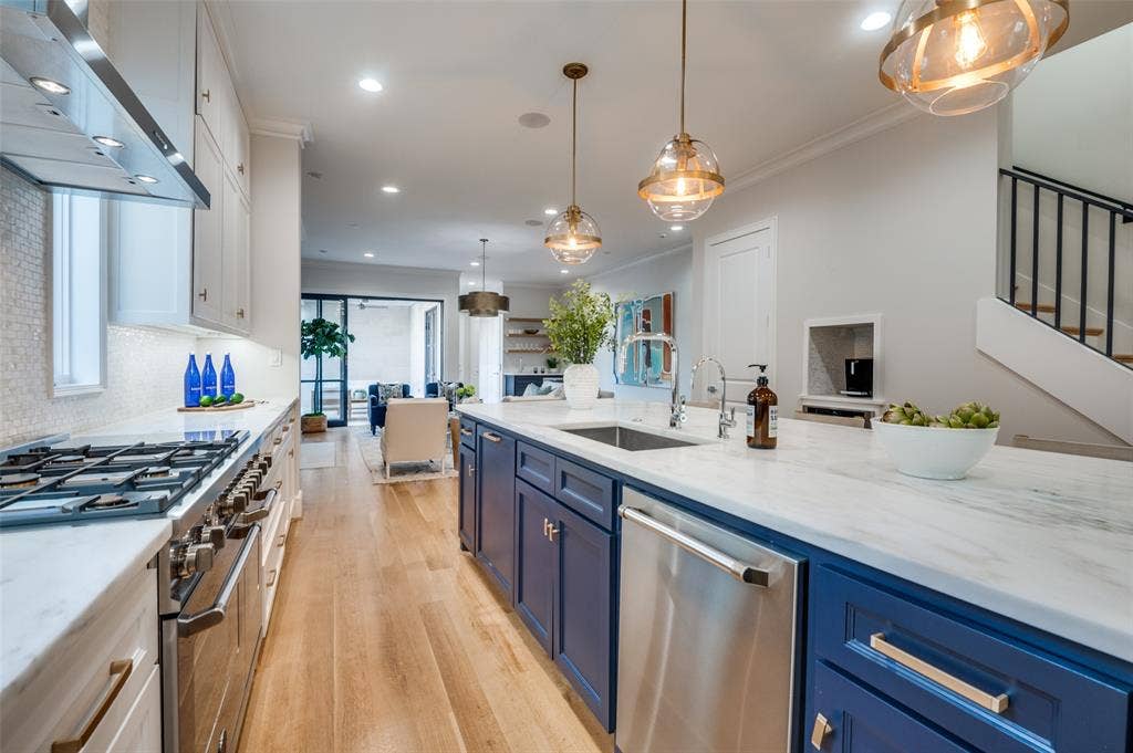 4031 Prescott Avenue, Dallas, TX 75219 Gourmet kitchen with stainless steel range, white quartz countertops, full-height white tile backsplash, and wood-finish flooring