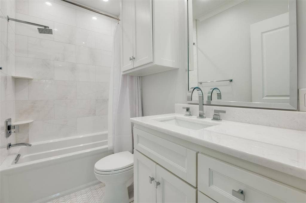 4031 Prescott Avenue, Dallas, TX 75219 Bathroom featuring a white vanity with integrated sink, chrome fixtures, built-in medicine cabinet, and white subway tile bath surround