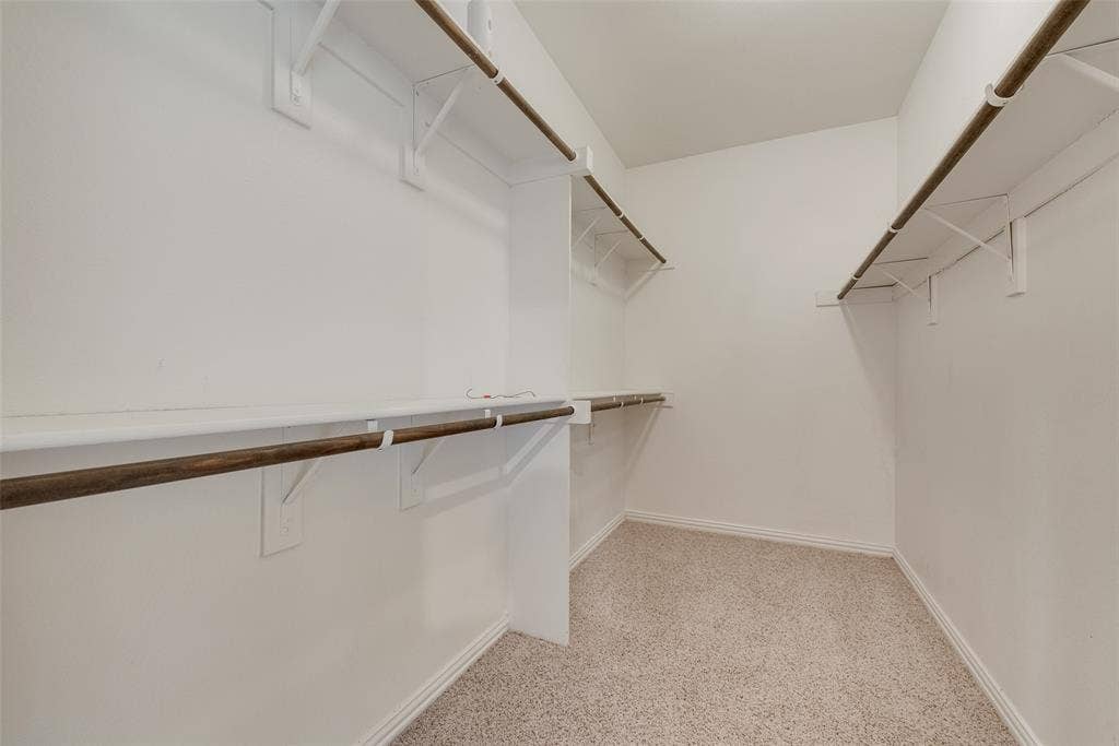 215 Fred Lane, Ferris, TX 75125 Carpeted walk-in closet featuring white walls, white shelving, and wood-finish hanging rods