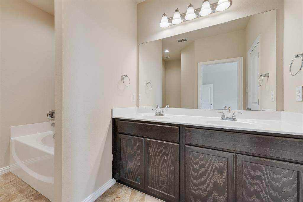 215 Fred Lane, Ferris, TX 75125 Dual basin vanity with white countertops, dark wood-finish cabinetry, and a full-width mirror