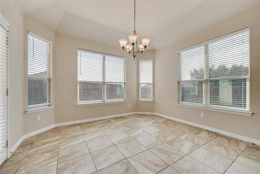 215 Fred Lane, Ferris, TX 75125 Recessed ceiling with a chandelier, bay windows with blinds, and square tile flooring