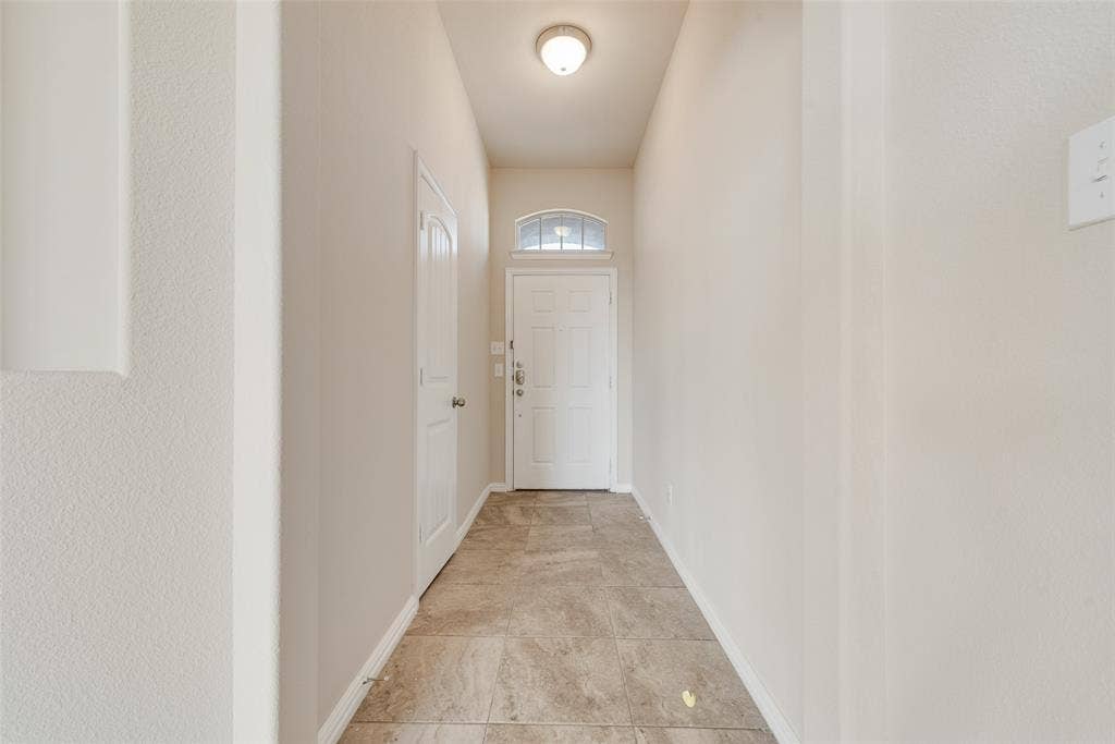 215 Fred Lane, Ferris, TX 75125 Foyer featuring ceramic tile flooring, a white paneled door with an arched transom, and a flush-mount ceiling light fixture
