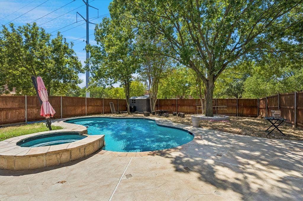 3800 Deer Forest Drive, Denton, TX 76208 In-ground pool with integrated spa, concrete decking, mature trees, wood privacy fencing, and an outdoor storage shed
