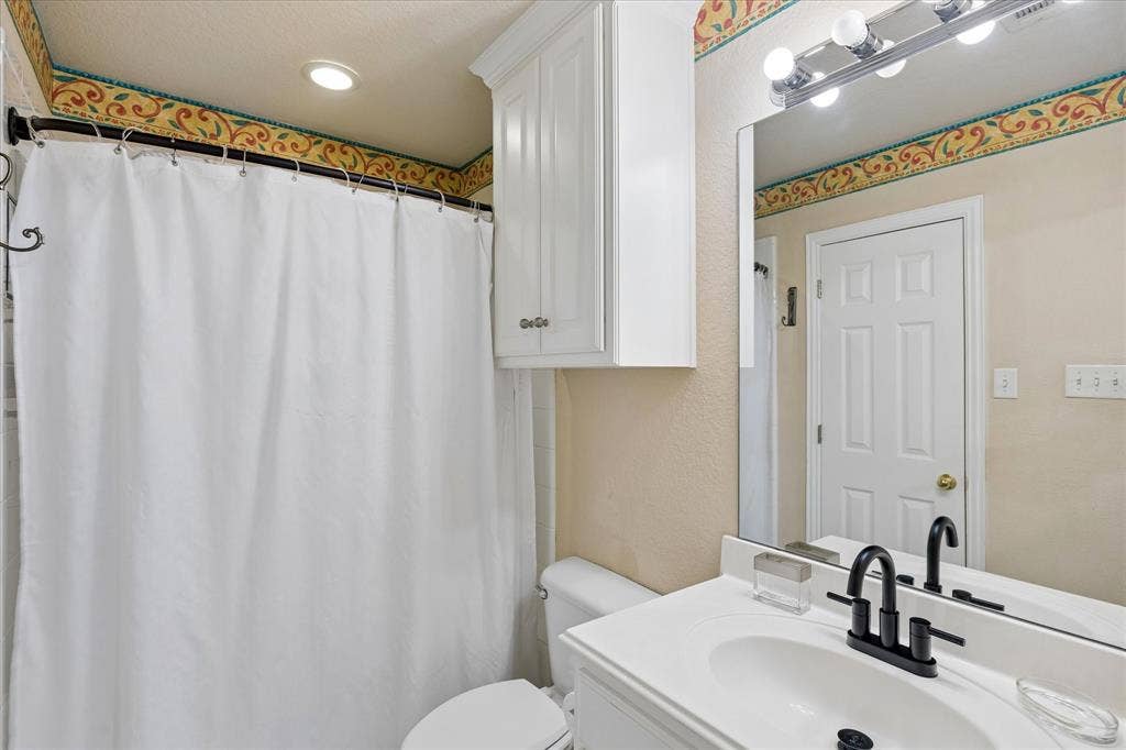 3800 Deer Forest Drive, Denton, TX 76208 White vanity with integrated sink, matte black faucet, wall-mounted mirror, and overhead vanity lighting
