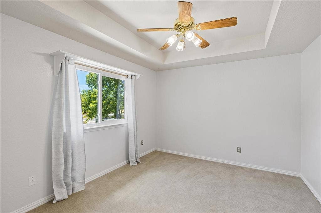 3800 Deer Forest Drive, Denton, TX 76208 Tray ceiling with a ceiling fan, white walls, and a large window