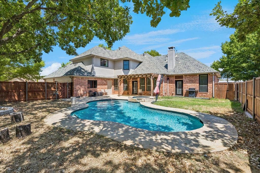 3800 Deer Forest Drive, Denton, TX 76208 Brick exterior with a multi-level roofline, in-ground swimming pool, and an attached spa