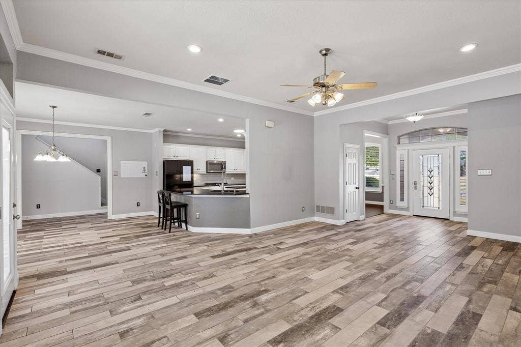 3800 Deer Forest Drive, Denton, TX 76208 Wood-finish flooring throughout, kitchen with white cabinetry and stainless steel appliances, recessed lighting, ceiling fan, and decorative glass entry door with sidelights