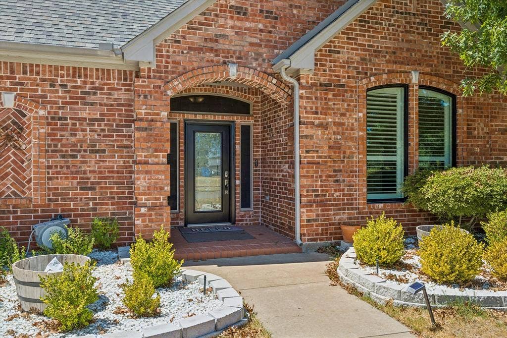 3800 Deer Forest Drive, Denton, TX 76208 Brick exterior with decorative herringbone detail, arched entryway, glass-paneled front door, and a curved walkway