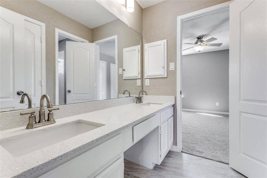 2822 Roundrock, McKinney, TX 75072 Dual vanity upstairs with integrated sinks, brushed nickel fixtures, white cabinetry, and a full-width mirror