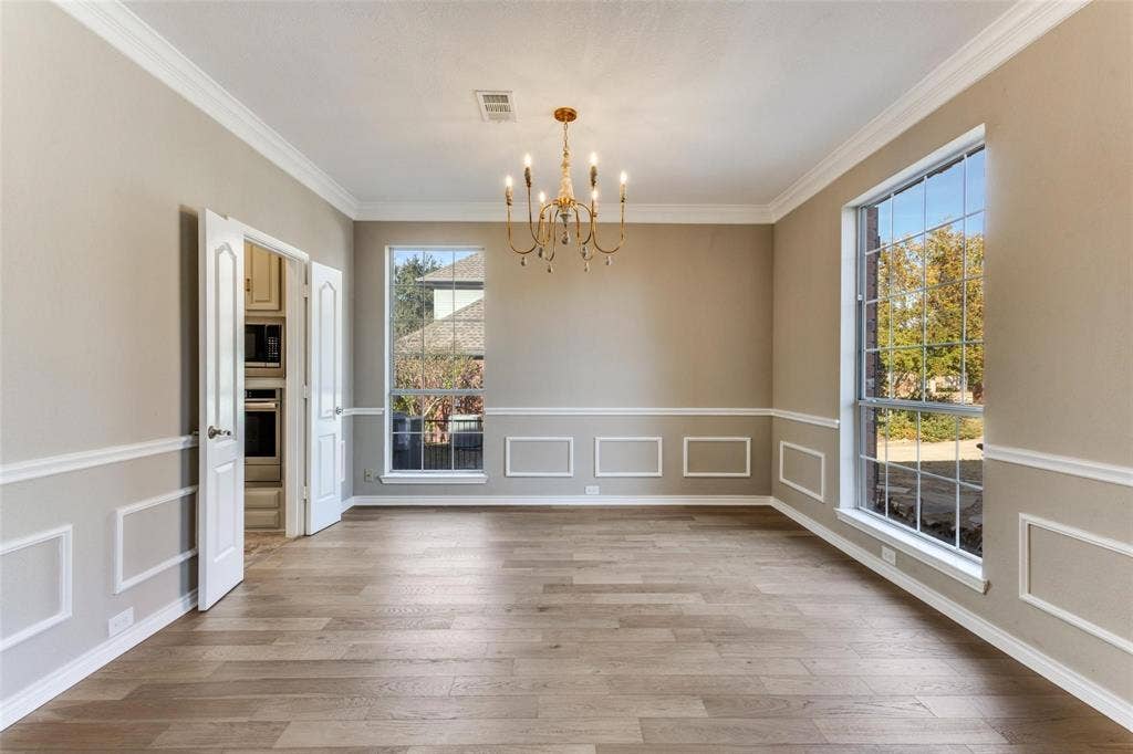 2822 Roundrock, McKinney, TX 75072 Wood-finish flooring, decorative wall molding, large window, double doors, and a gold-tone chandelier
