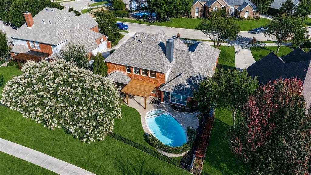 2822 Roundrock, McKinney, TX 75072 Brick exterior with a gabled roof, featuring a backyard pool, wooden pergola, and lush green lawn