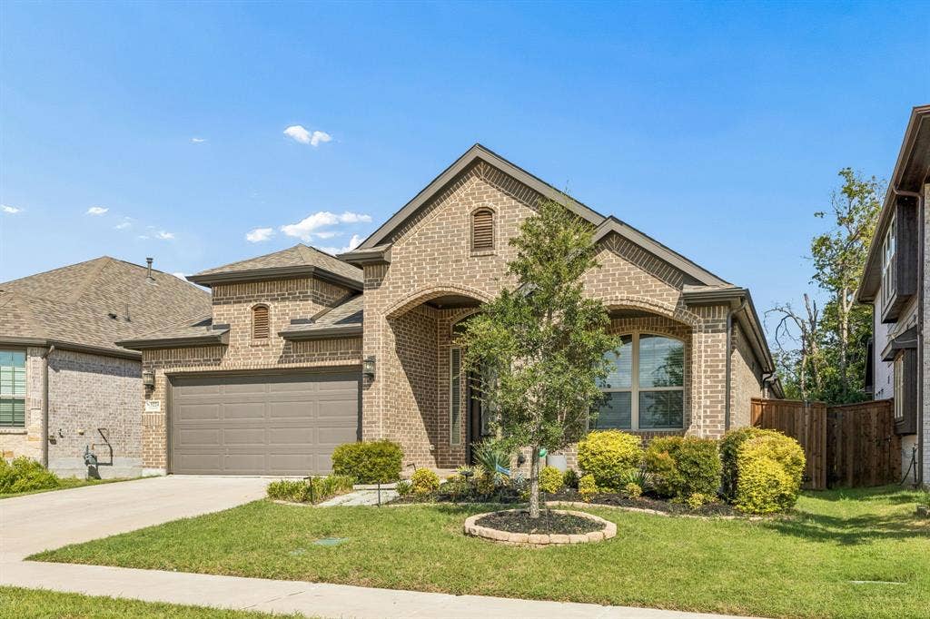 5224 Troupe Road, McKinney, TX 75071 Brick exterior with stone accents, arched entry, two-car garage, and established landscaping