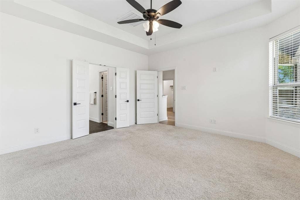5224 Troupe Road, McKinney, TX 75071 Tray ceiling with a ceiling fan, plush carpet flooring, multiple panel doors, and a window with blinds