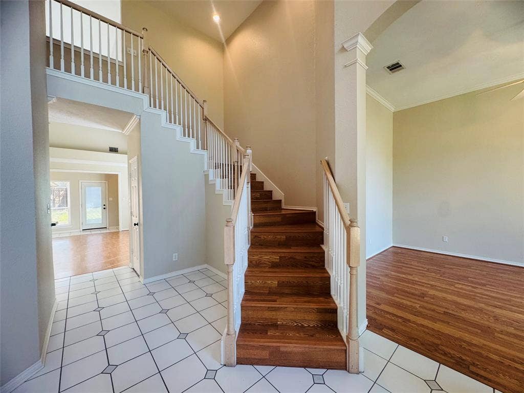 Two-story entry with a wood-finish staircase, tile flooring, and a second-story landing