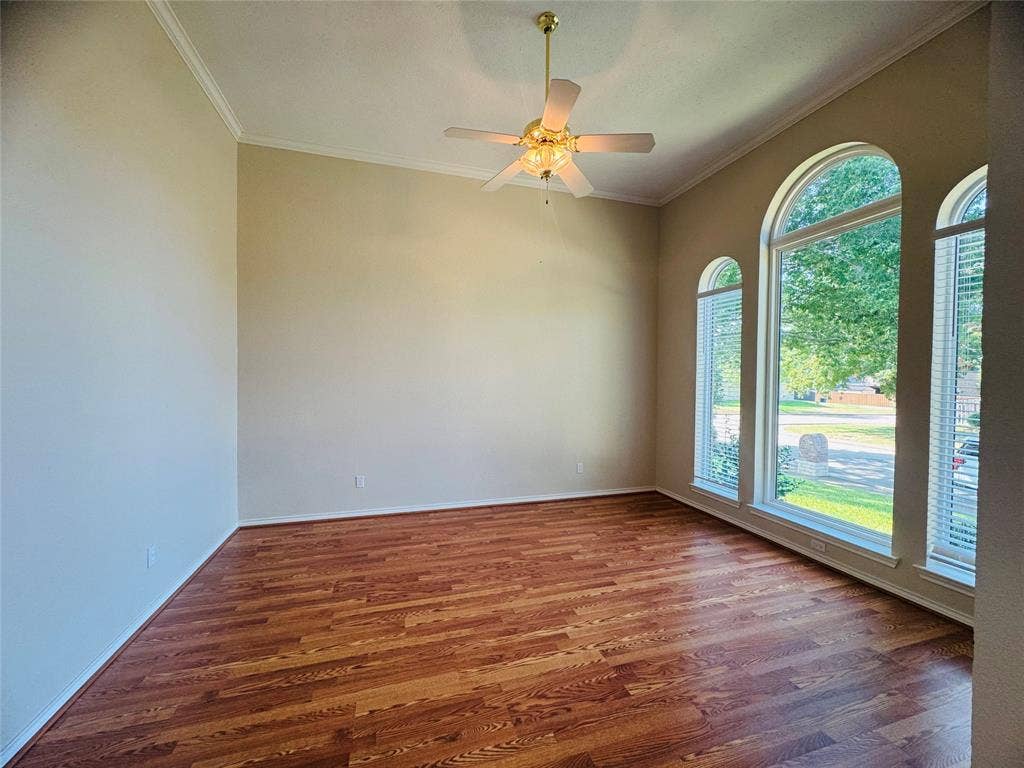 Vaulted ceiling with crown molding, wood-finish flooring, and multiple arched windows