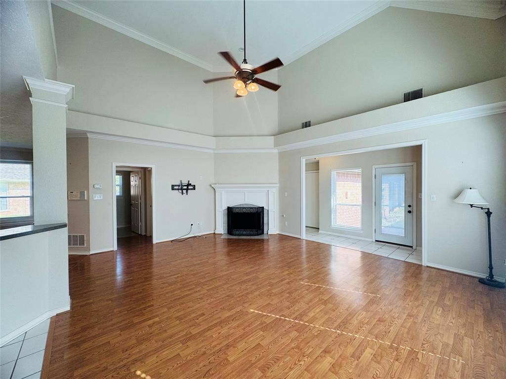 Vaulted ceilings, wood-finish flooring, white mantel, and a ceiling fan with integrated lighting