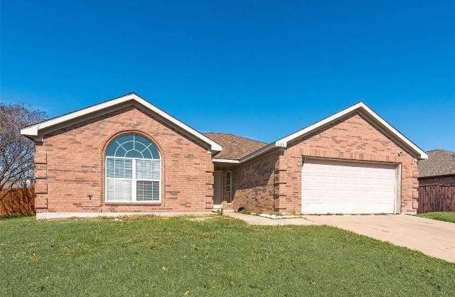 1405 Teal Way, Midlothian, TX 76065 Brick exterior with arched window detail and white trim accents, two-car garage with white overhead door, and manicured front lawn with mature landscaping