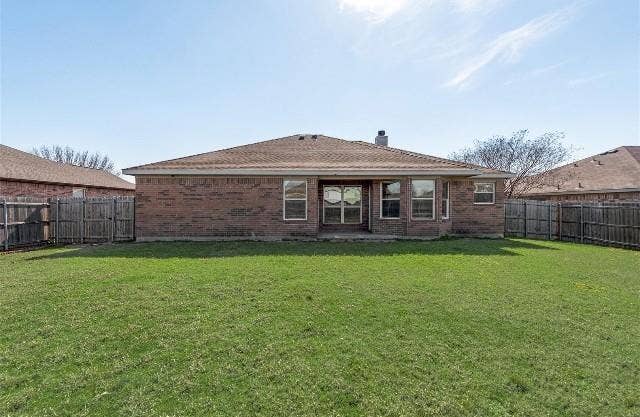 1405 Teal Way, Midlothian, TX 76065 Expansive backyard featuring a manicured lawn, brick exterior, multiple windows, and a wood privacy fence