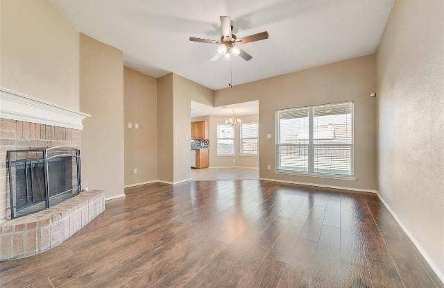 1405 Teal Way, Midlothian, TX 76065 Vaulted ceiling with a ceiling fan, brick-clad fireplace with a white mantel, wood-finish flooring, and large windows with blinds
