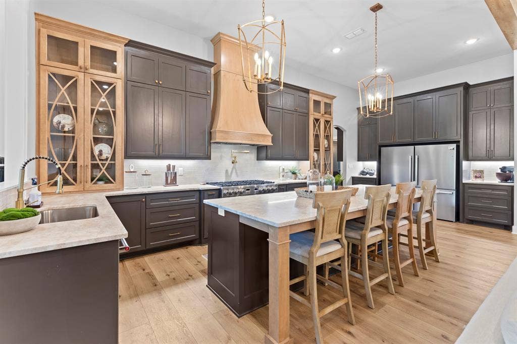23180 Bridle View Drive, Lindale, TX 75771 Kitchen featuring wood-finish flooring, two-tone cabinetry, stainless steel appliances, a center island with countertop seating, and recessed lighting