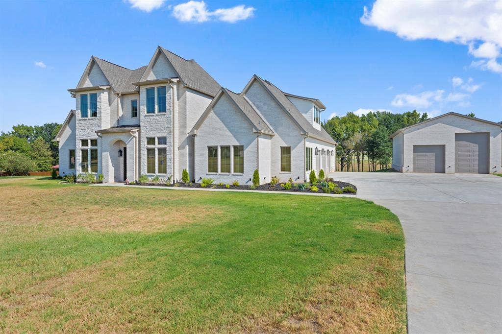 23180 Bridle View Drive, Lindale, TX 75771 Stately residence featuring a light-colored brick and stone exterior, multiple gables, a covered entry, and a dedicated detached garage structure