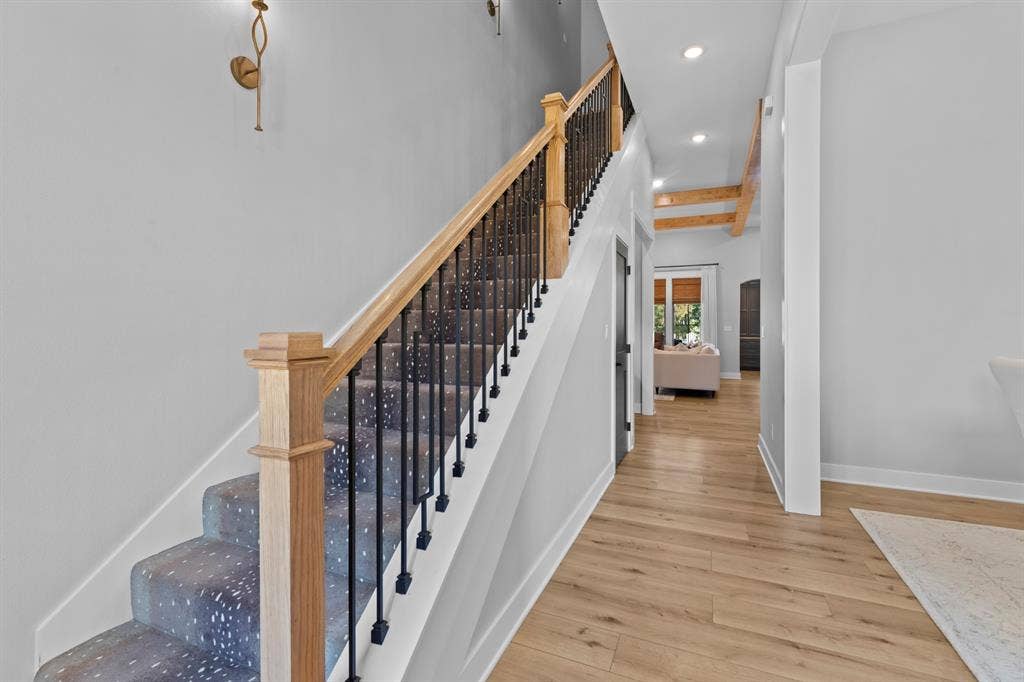 23180 Bridle View Drive, Lindale, TX 75771 Staircase with wood newel post and handrail, black wrought iron balusters, and patterned carpet runner