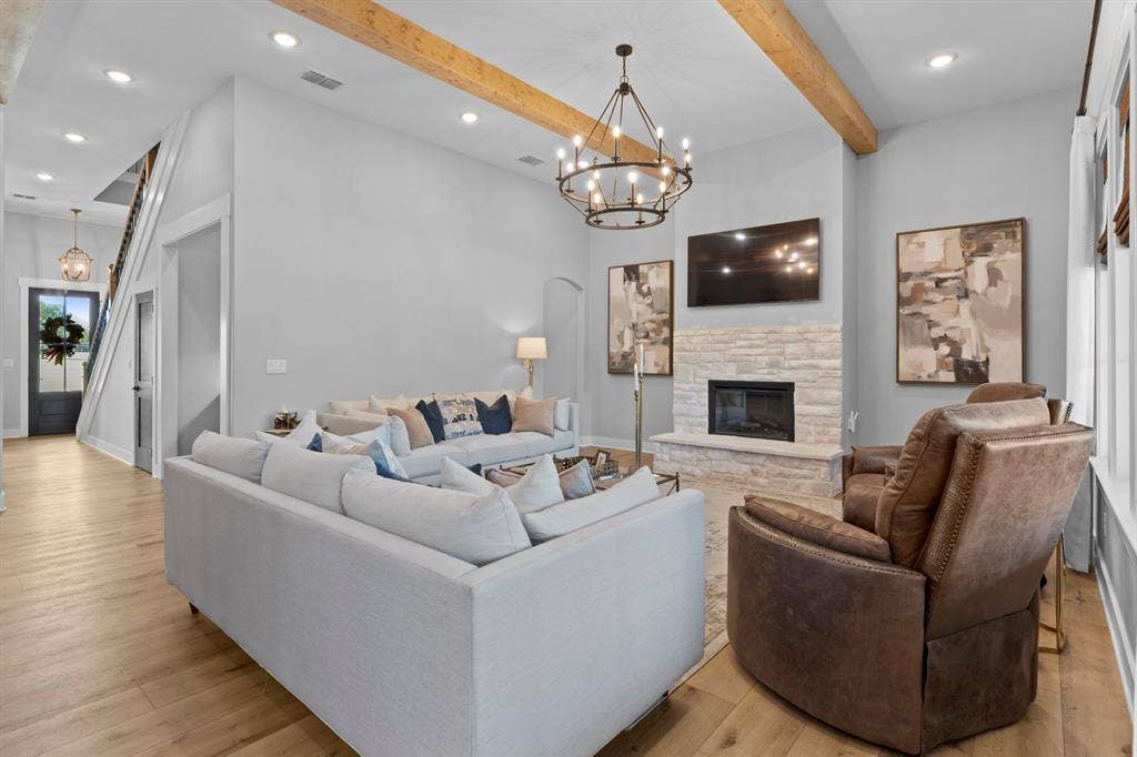 23180 Bridle View Drive, Lindale, TX 75771 Vaulted ceiling with exposed wood beams, stone-faced fireplace, wood-finish flooring, and a wrought iron chandelier
