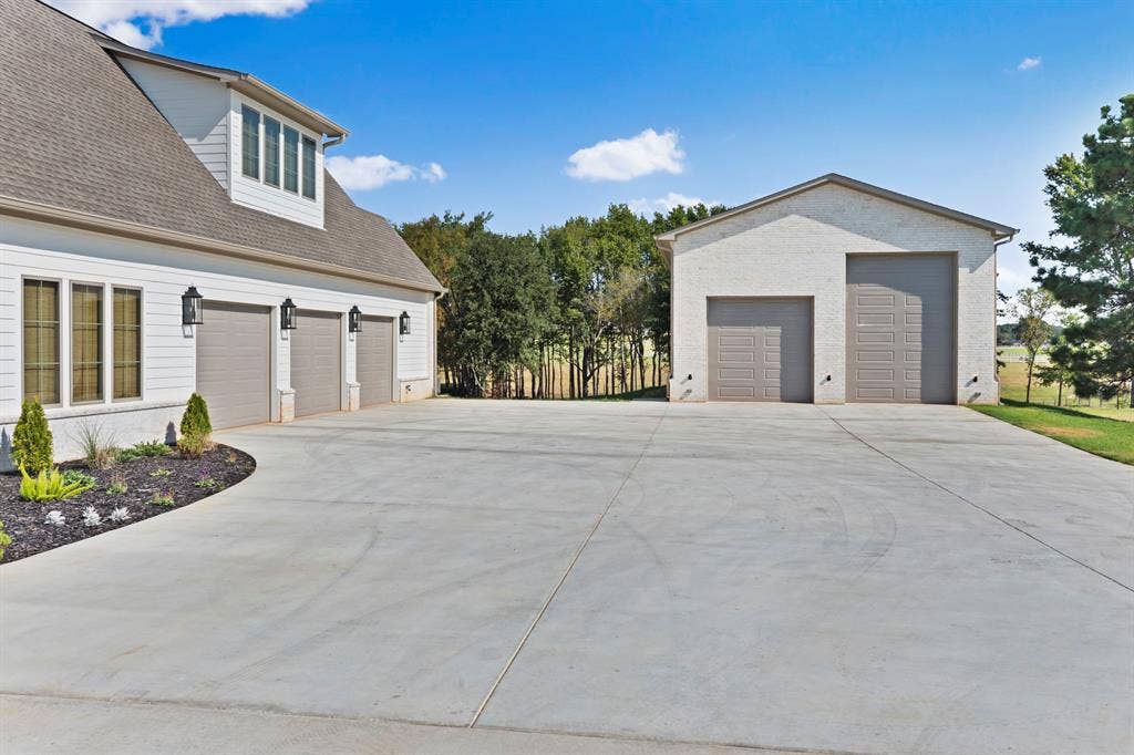 23180 Bridle View Drive, Lindale, TX 75771 Three-car attached garage with white siding, dormer windows, and black exterior lighting