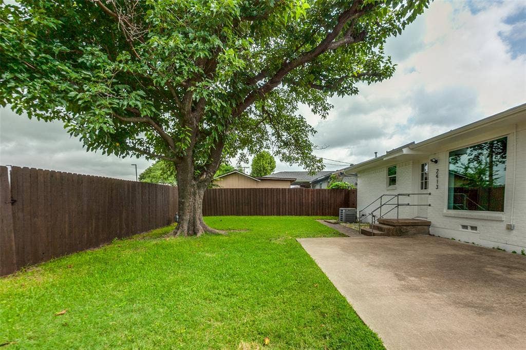 2413 Patricia Lane, Garland, TX 75041 Backyard with large tree and cement patio