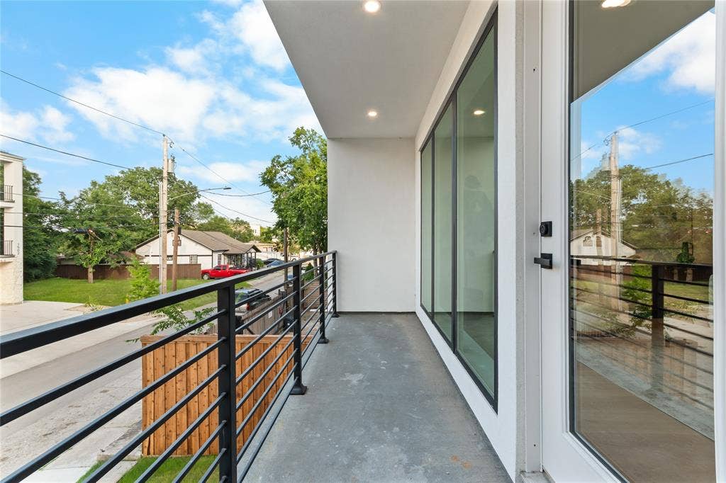 Private balcony featuring a concrete surface, black horizontal bar railing, and recessed lighting