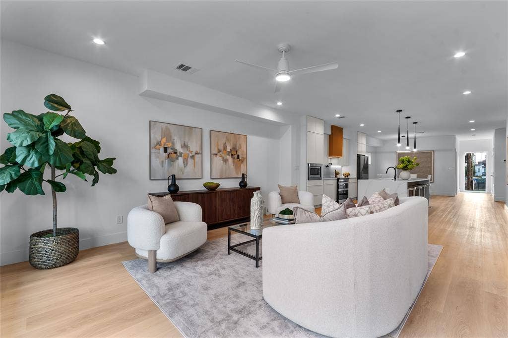 Open-concept living area with light wood-finish flooring, recessed lighting, and a modern ceiling fan