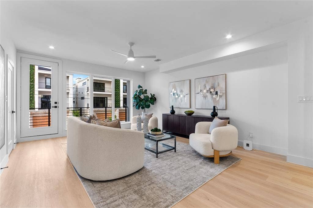Spacious living area featuring light wood-finish flooring, recessed lighting, and a contemporary ceiling fan