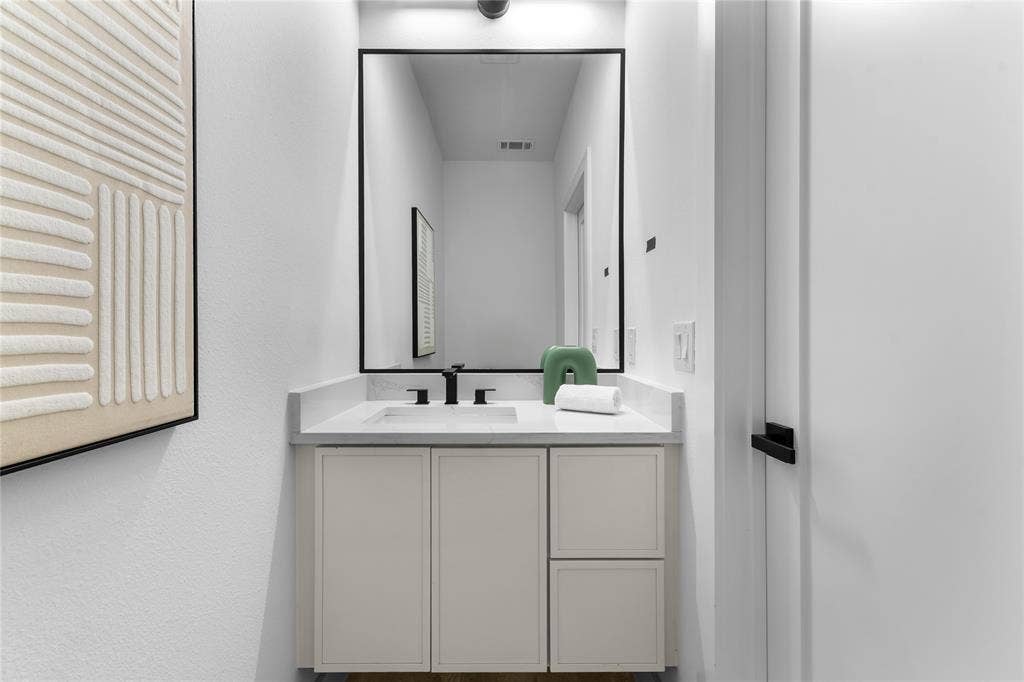 Modern bathroom vanity featuring a light-toned cabinet, integrated sink, and stone-finish countertop