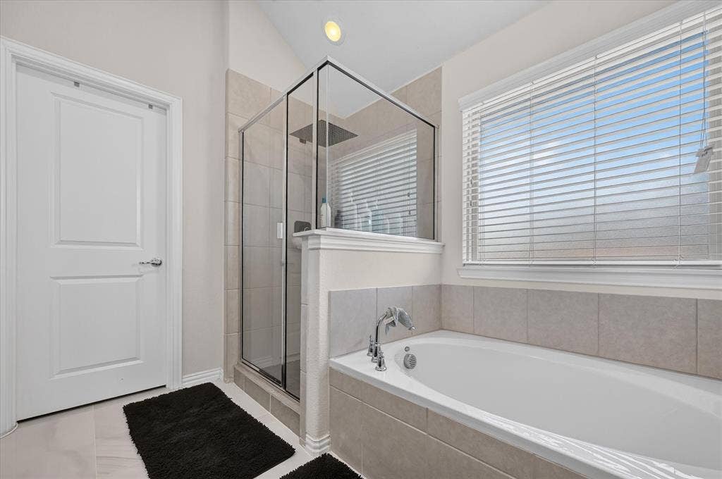 2025 Lake Front Trail, Garland, TX 75043 Soaking tub with tile surround, glass-enclosed shower, large window with blinds, and recessed lighting
