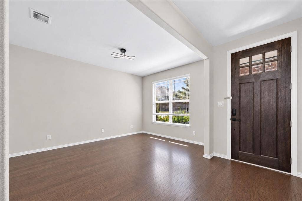 2025 Lake Front Trail, Garland, TX 75043 Rich wood-finish flooring, a modern flush-mount light fixture, and a dark wood entry door with glass panes complement the neutral wall finishes