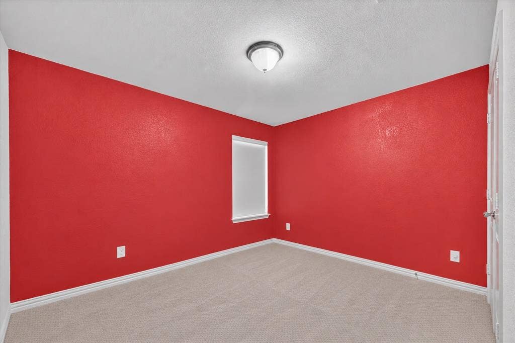 2025 Lake Front Trail, Garland, TX 75043 Red wall finish, neutral carpet flooring, single window with white trim, flush-mount ceiling light fixture, and white painted door