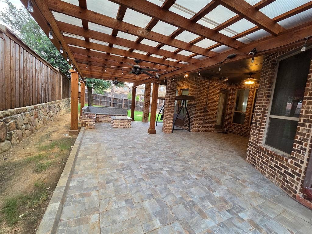 146 Rolling Fork Bend, Irving, TX 75039 Expansive covered patio featuring a wood pergola with translucent roofing, string lighting, and ceiling fans