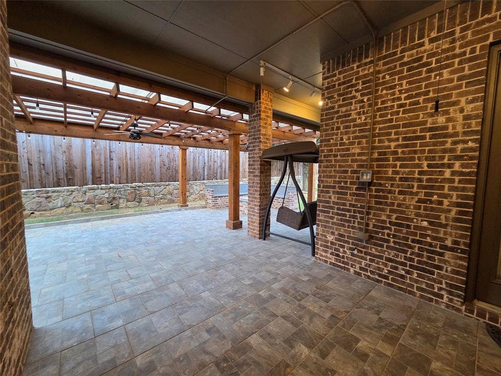 146 Rolling Fork Bend, Irving, TX 75039 Expansive brick patio featuring paver flooring, a wooden pergola, and a stone retaining wall