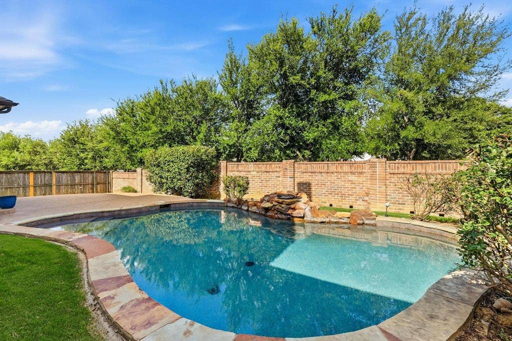 420 Silverado Trail, Keller, TX 76248 Swimming pool with a stone waterfall feature, concrete decking, stone coping, and a brick privacy wall