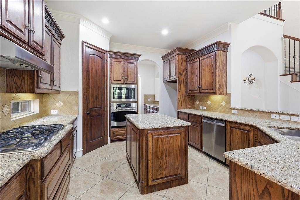 420 Silverado Trail, Keller, TX 76248 Kitchen featuring wood cabinetry, light-toned stone countertops, built-in stainless steel appliances, and tile flooring