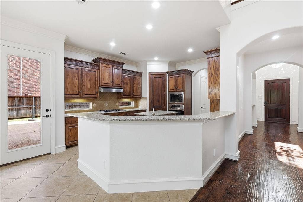 420 Silverado Trail, Keller, TX 76248 Kitchen featuring wood cabinetry, built-in stainless steel appliances, and a breakfast bar with a light-toned countertop