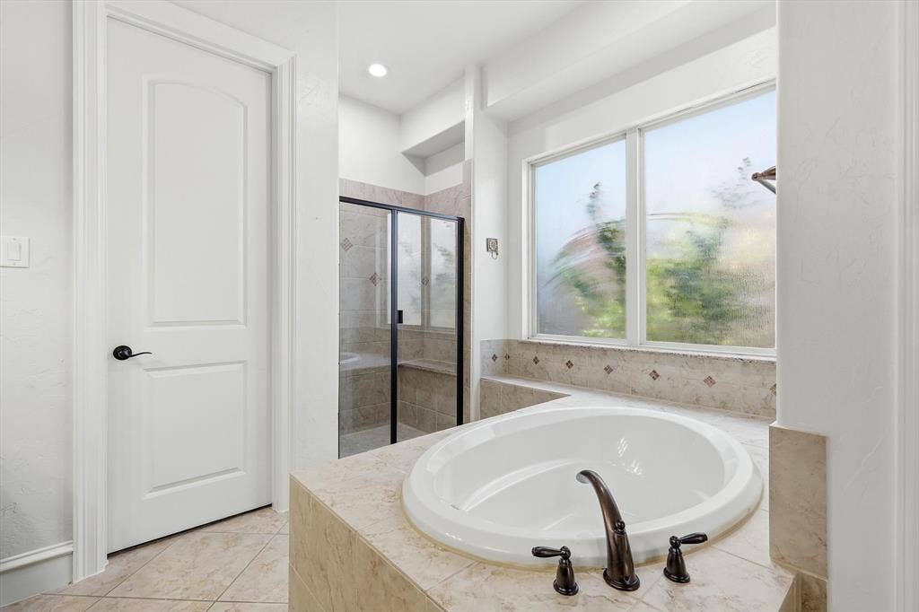 420 Silverado Trail, Keller, TX 76248 Built-in soaking tub with dark bronze fixtures, tile surround, and an adjacent multi-pane window