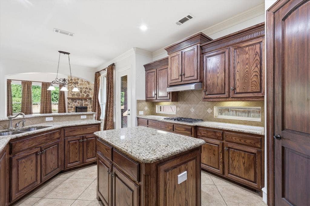 420 Silverado Trail, Keller, TX 76248 Kitchen featuring a central island, wood cabinetry, granite countertops, and tile flooring