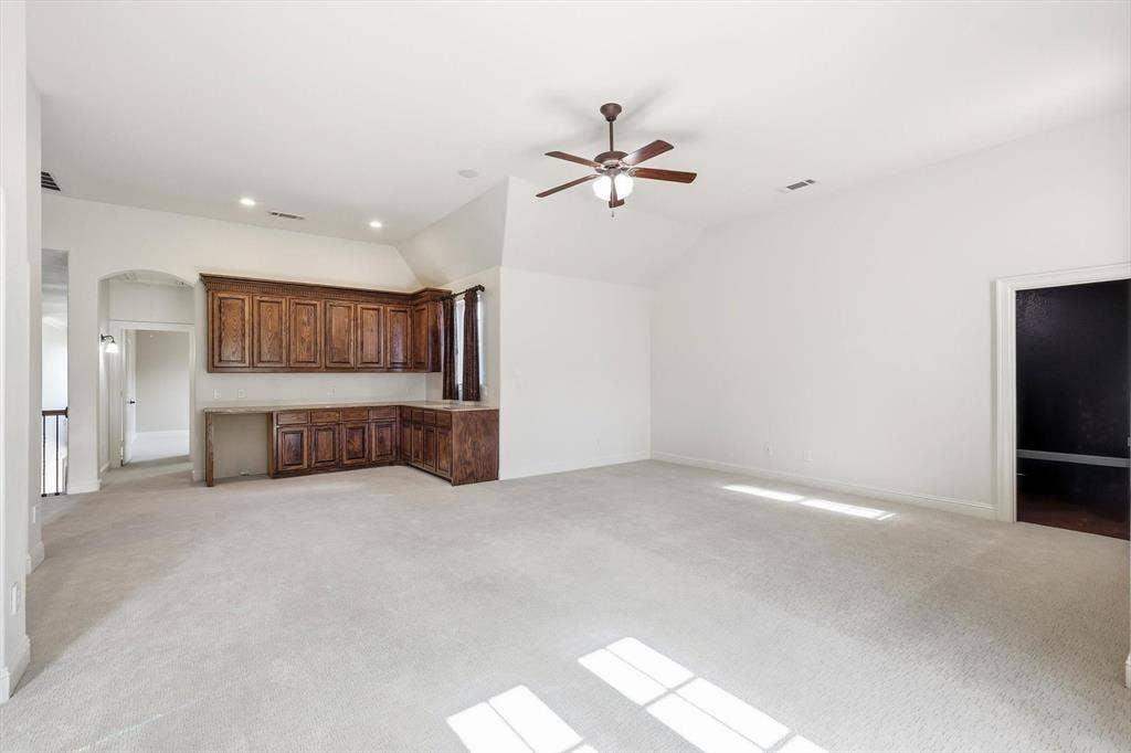 420 Silverado Trail, Keller, TX 76248 Vaulted ceiling with a ceiling fan, recessed lighting, built-in wood cabinetry, light-toned carpeting, and an arched entryway