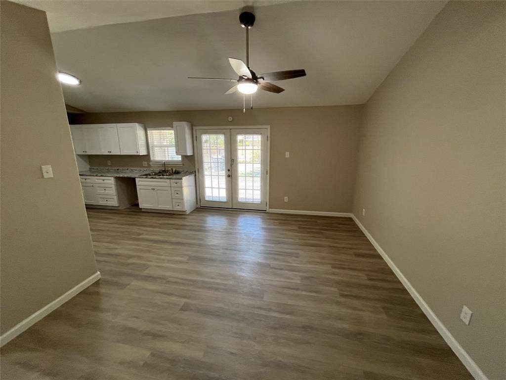 9615 Oak Gate Lane, Dallas, TX 75217 Vaulted ceiling with a ceiling fan, wood-finish flooring, white cabinetry, integrated sink, and double glass-paned doors